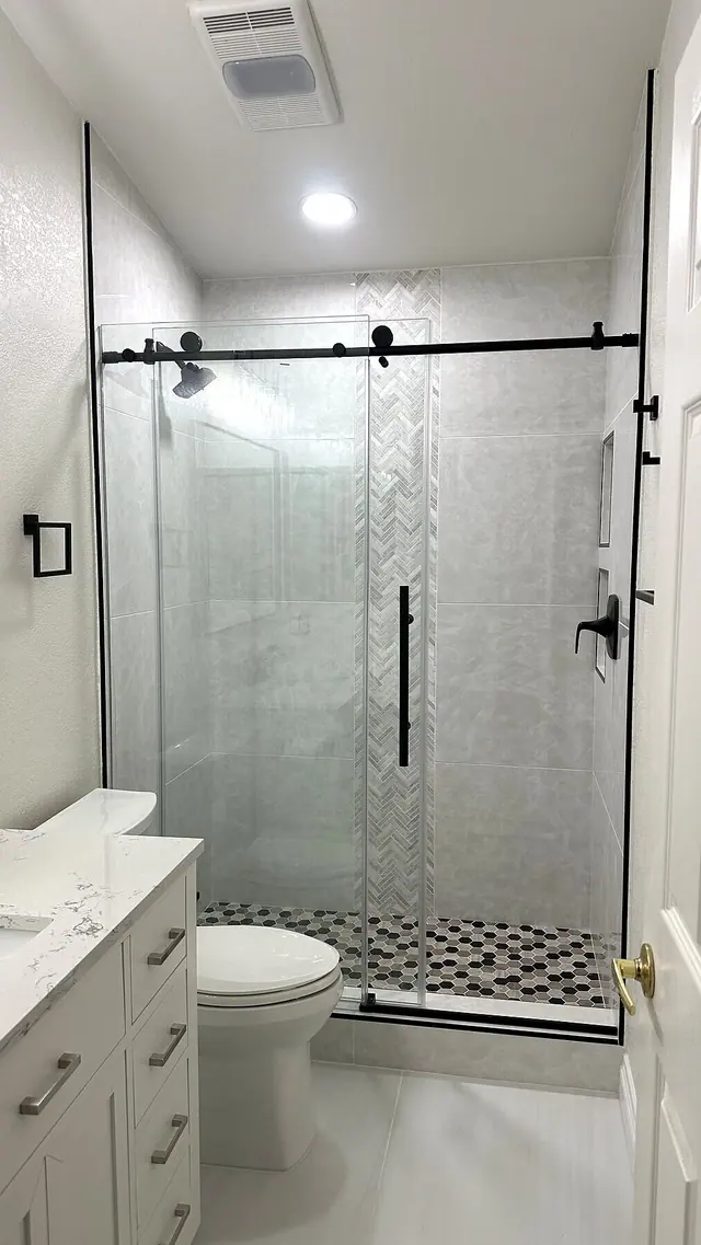 Frameless glass shower remodel with white tile and black hardware