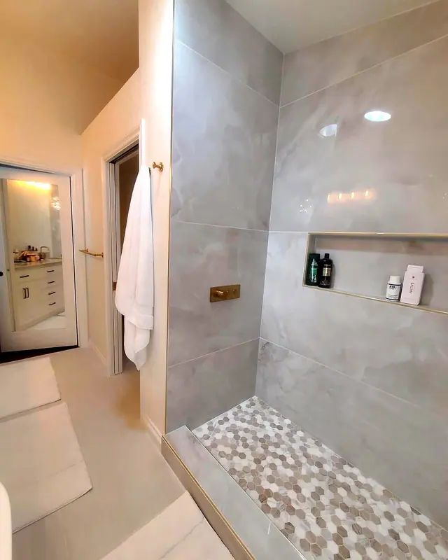 Gray tile shower remodel with pebble shower floor and built-in niche