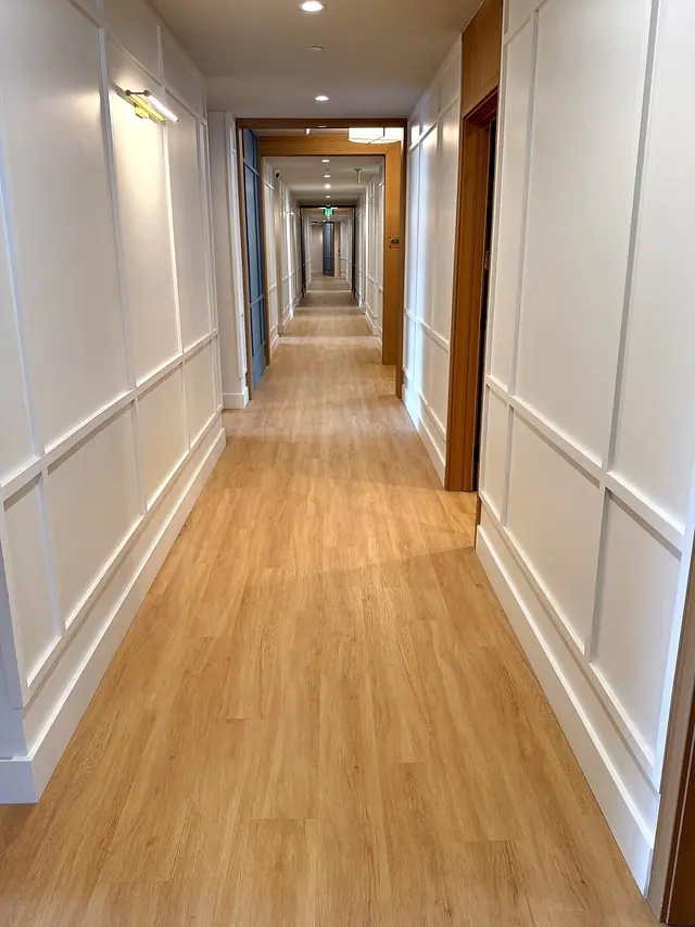 Long hallway with light wood flooring and white wall trim
