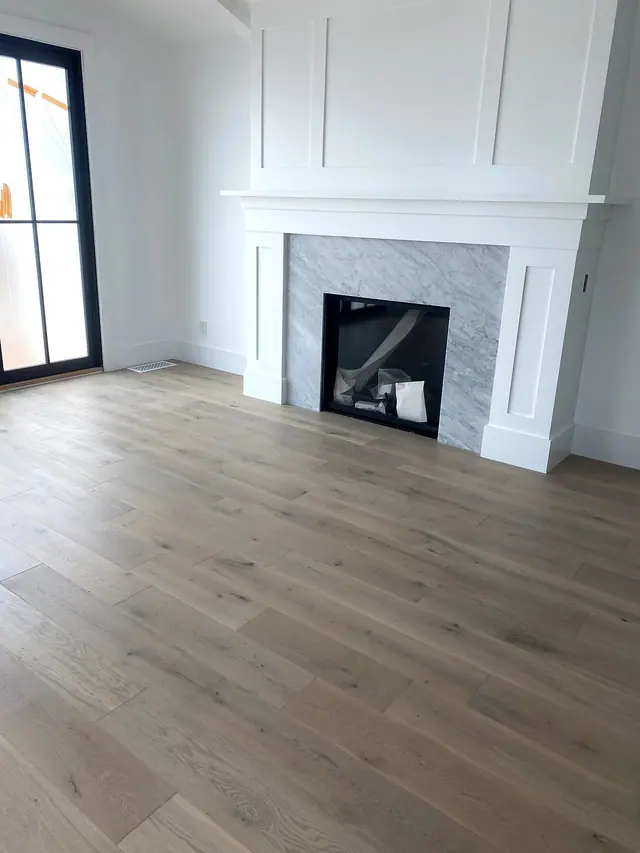 Light oak flooring with fireplace trim and white wall detail