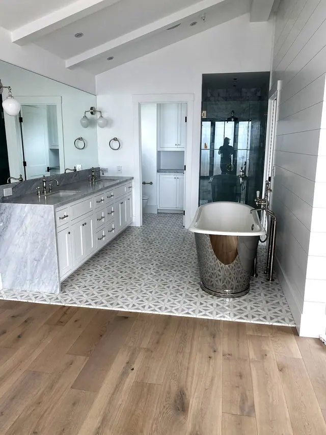 Primary bathroom remodel with freestanding tub, walk-in shower, vanity, and light wood flooring